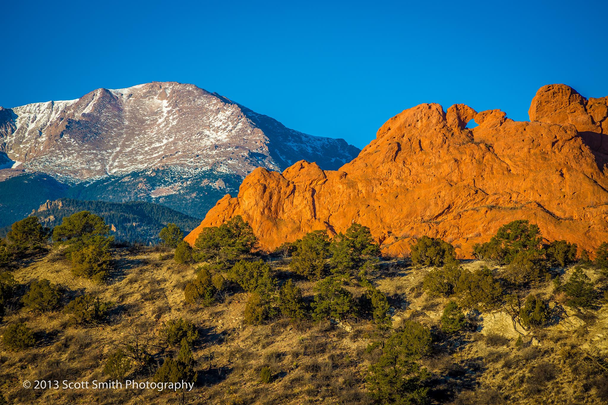Sun rising on the Garden of the Gods - The Garden of the Gods earlier in the morning with Pike's Peak in the background. by Scott Smith Photos