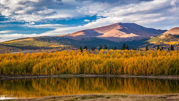 A small lake between South Park and Fairplay, Colorado reflects the fall aspens as the sun sets on a beautiful weekend.